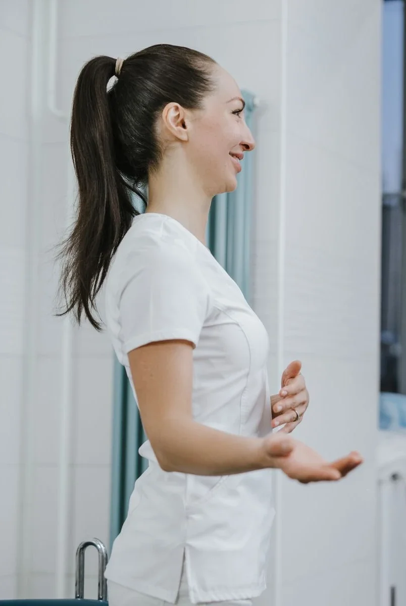 A nurse in white scrubs smiling during a conversation
